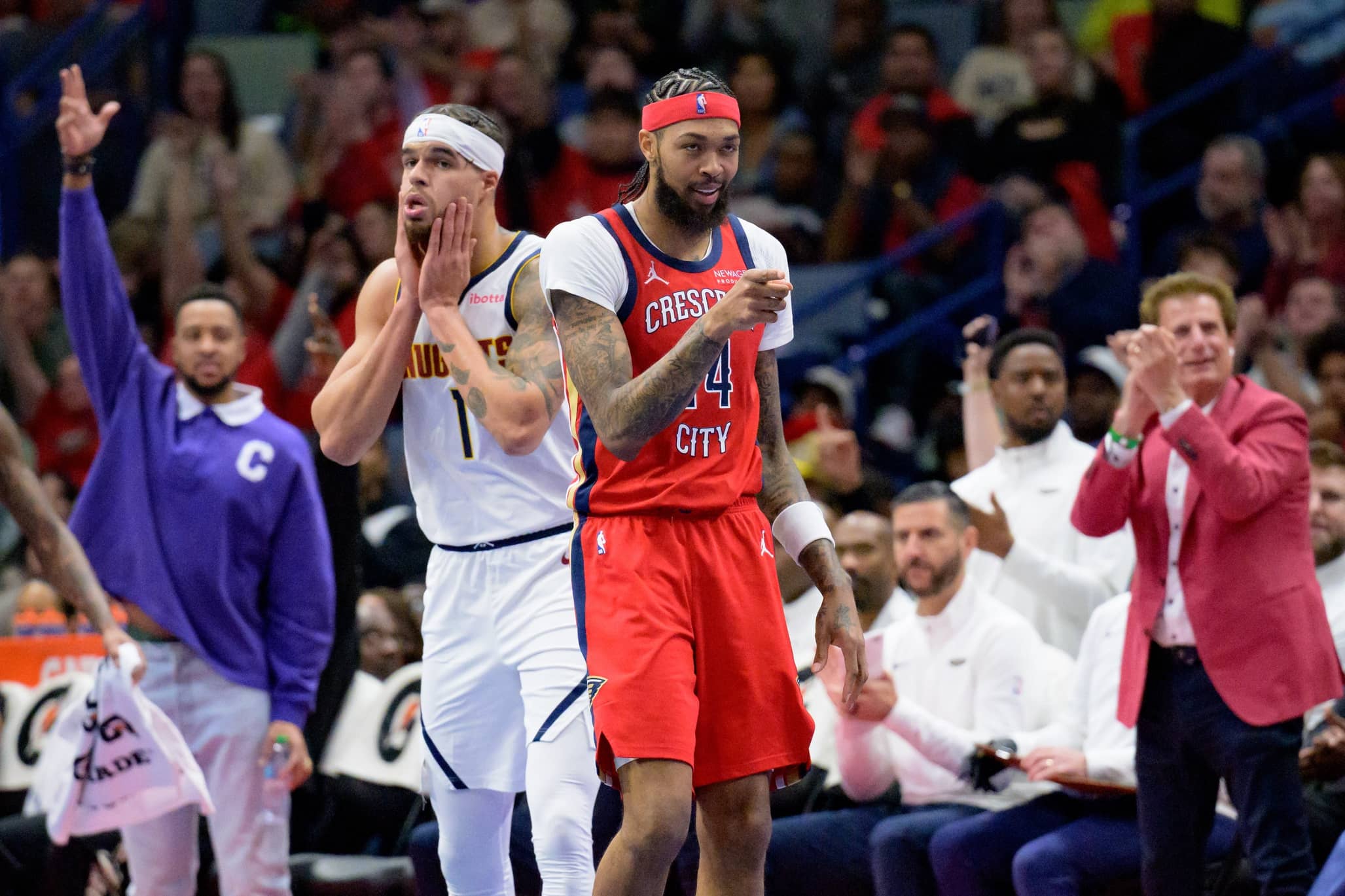 Nov 15, 2024; New Orleans, Louisiana, USA; New Orleans Pelicans forward Brandon Ingram (14) celebrates a three point basket by guard Jaylen Nowell (not pictured) next to Denver Nuggets forward Michael Porter Jr. (1) during the first half at Smoothie King Center.
