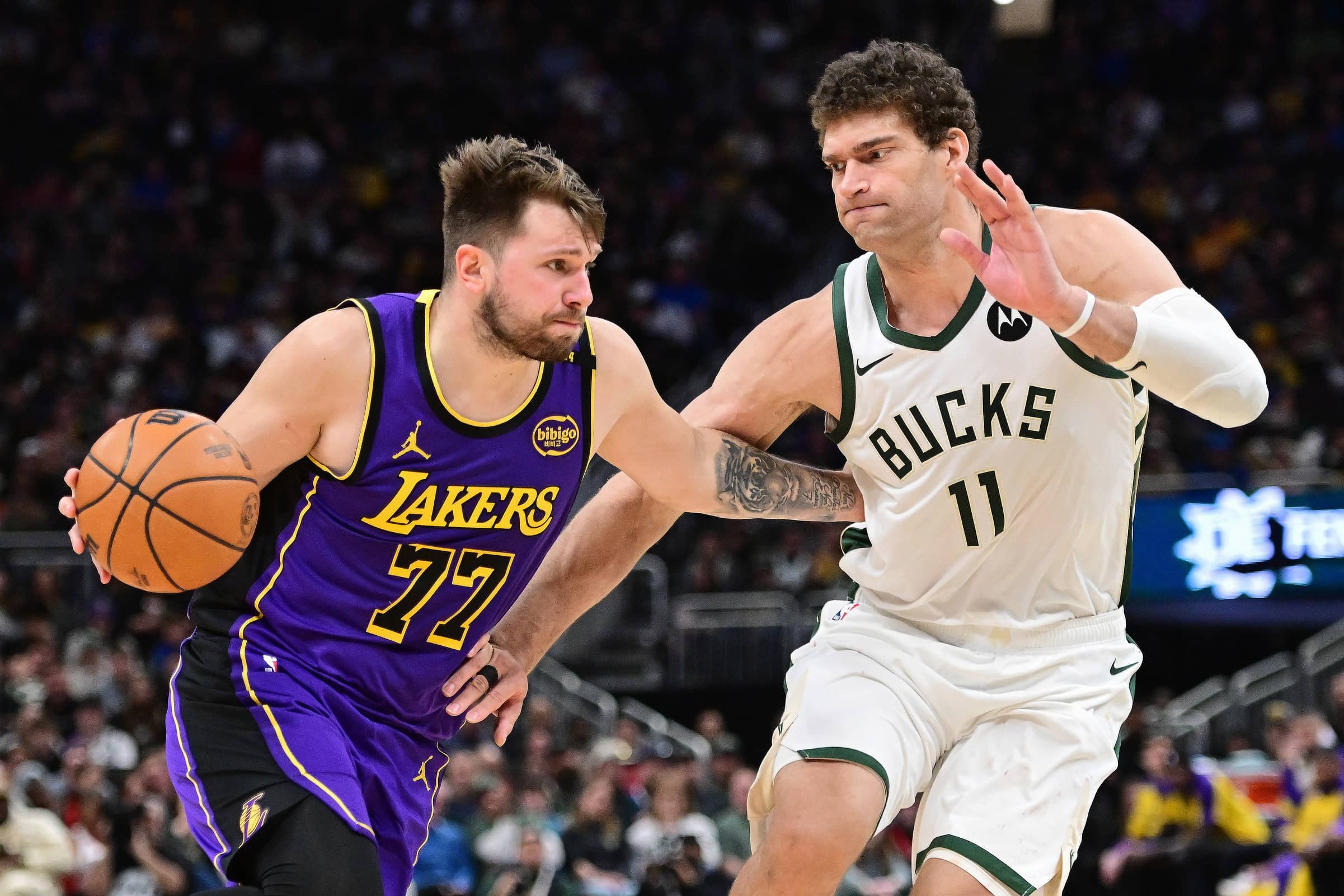Mar 13, 2025; Milwaukee, Wisconsin, USA; Los Angeles Lakers guard Luka Doncic (77) drives to the basket against Milwaukee Bucks center Brook Lopez (11) in the fourth quarter at Fiserv Forum. Mandatory Credit: Benny Sieu-Imagn Images