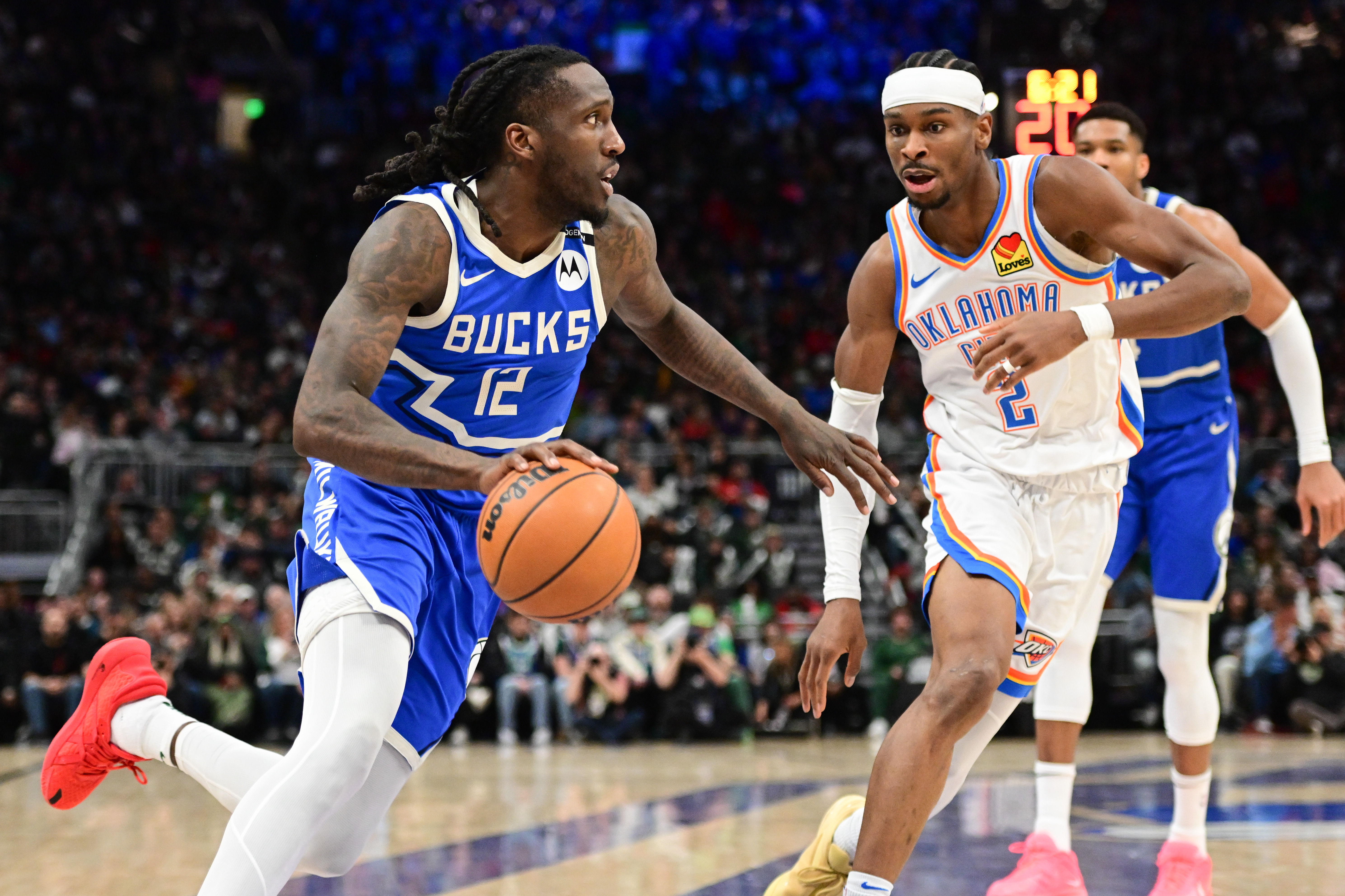 Mar 16, 2025; Milwaukee, Wisconsin, USA; Milwaukee Bucks guard Taurean Prince (12) drives for the basket against Oklahoma City Thunder guard Shai Gilgeous-Alexander (2) in the third quarter at Fiserv Forum. Mandatory Credit: Benny Sieu-Imagn Images  
