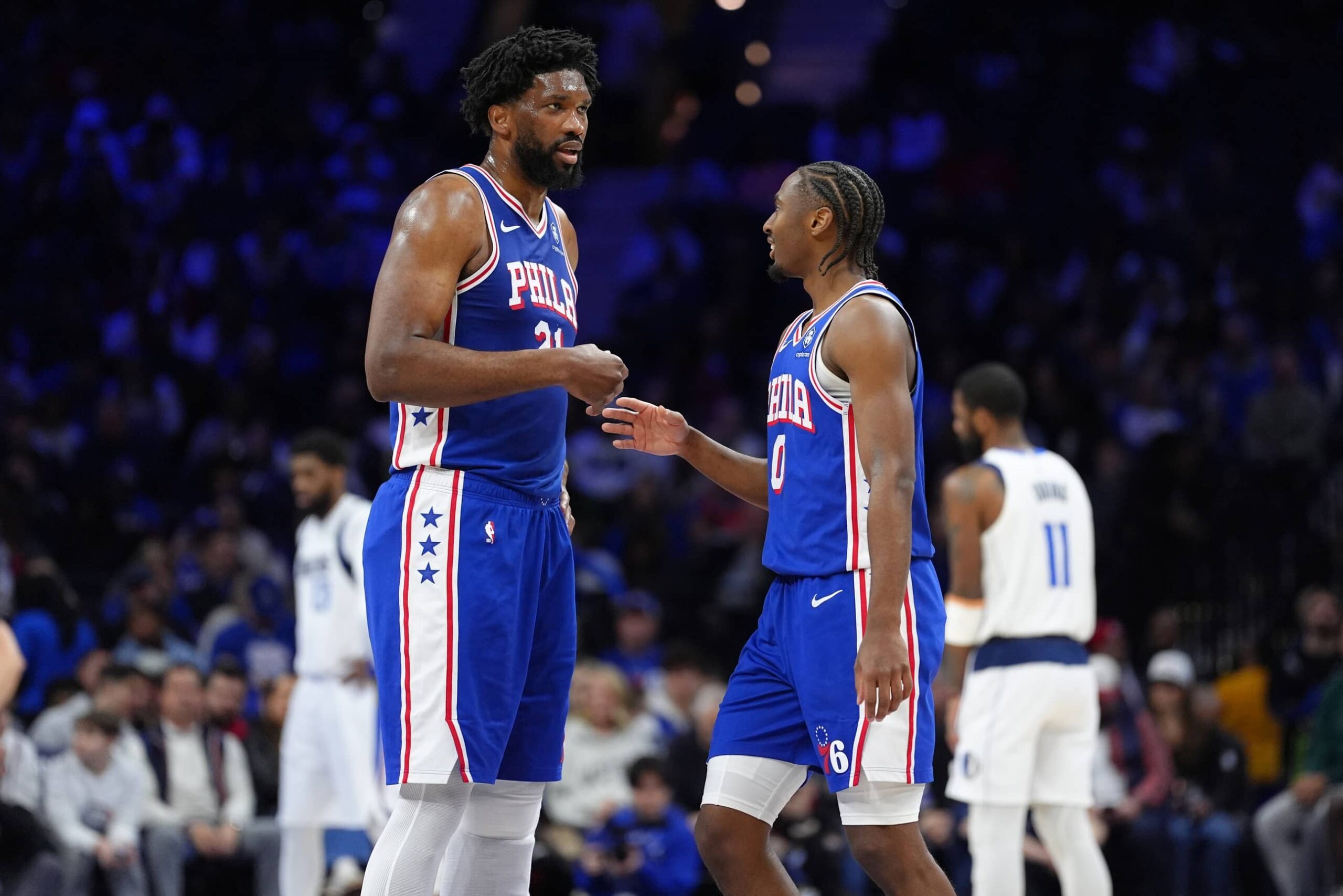 Joel Embiid and Tyrese Maxey in discussion during a game.