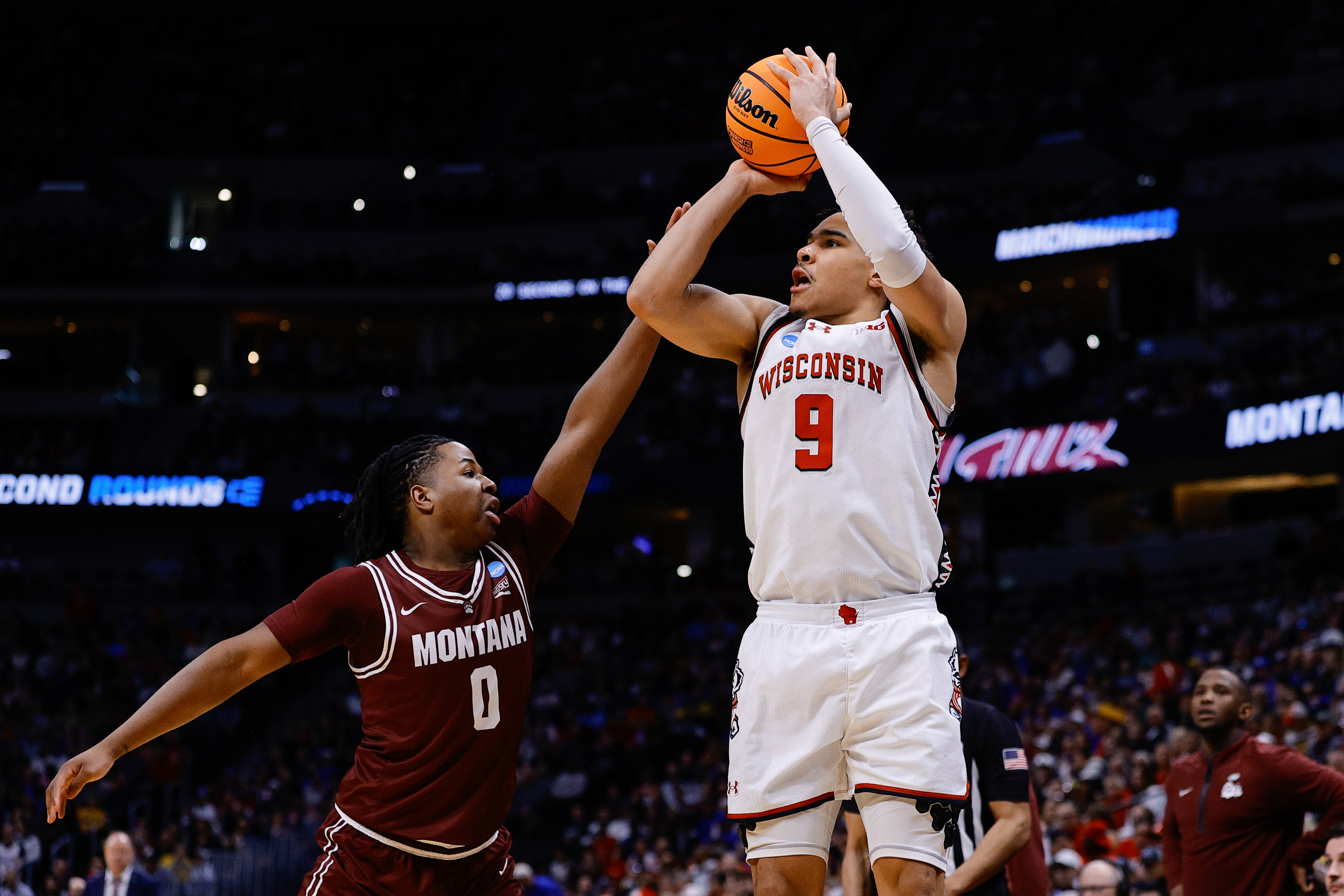 Mar 20, 2025; Denver, CO, USA; Wisconsin Badgers guard John Tonje (9) shoots the ball against Montana Grizzlies guard Money Williams (0) during the first half in the first round of the NCAA Tournament at Ball Arena. Mandatory Credit: Isaiah J. Downing-Imagn Images  