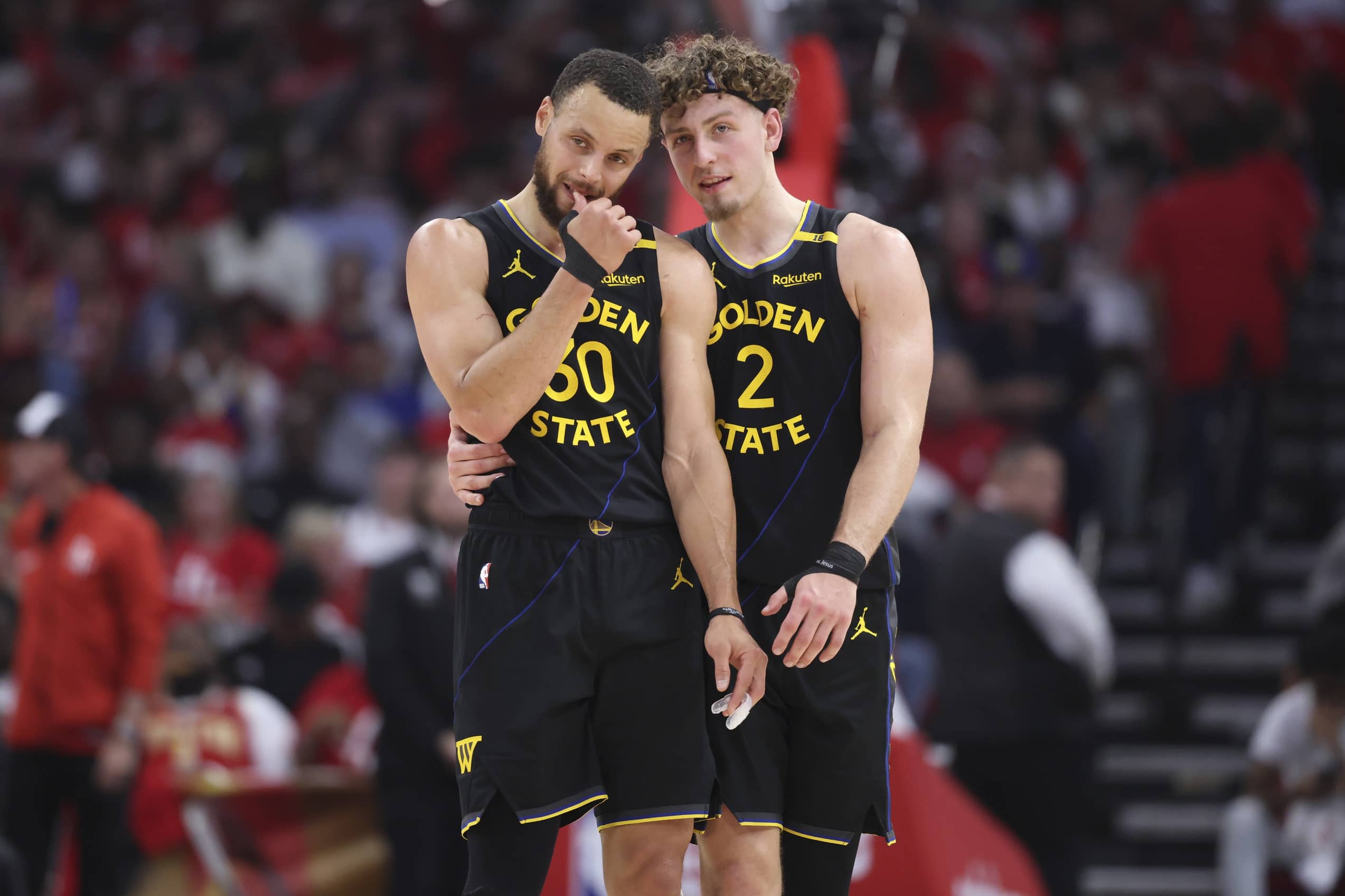 Warriors guard Stephen Curry and guard Brandin Podziemski talk during a timeout during game seven of first round for the 2025 NBA Playoffs against the Rockets at Toyota Center.