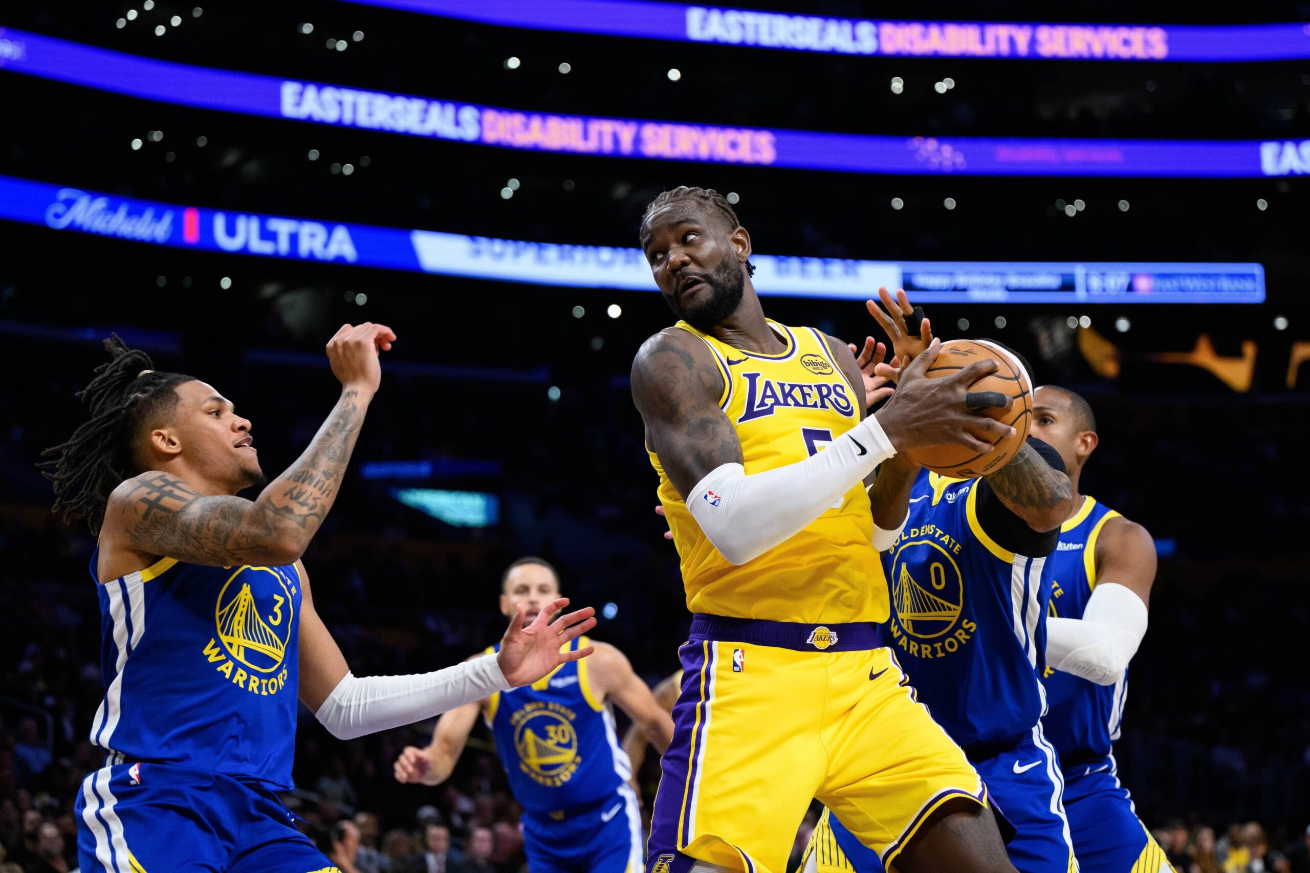 Oct 21, 2025; Los Angeles, California, USA; Los Angeles Lakers center Deandre Ayton (5) grabs a rebound against Golden State Warriors guard Gary Payton II (0) during the first half at Crypto.com Arena. Mandatory Credit: William Liang-Imagn Images