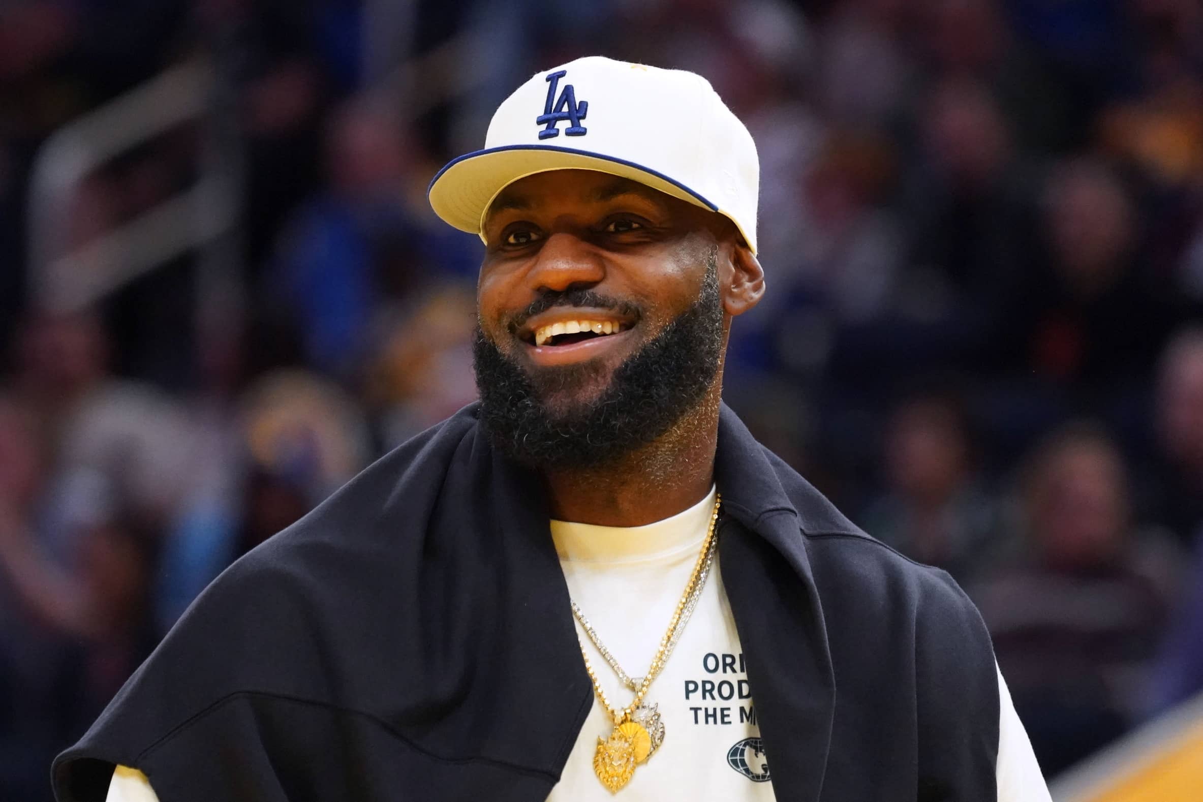 San Francisco, California, USA; Los Angeles Lakers forward LeBron James (23), wearing a Los Angeles Dodgers hat, watches from the sideline during a break against the Golden State Warriors in the third quarter at Chase Center. Mandatory Credit: David Gonzales-Imagn Images