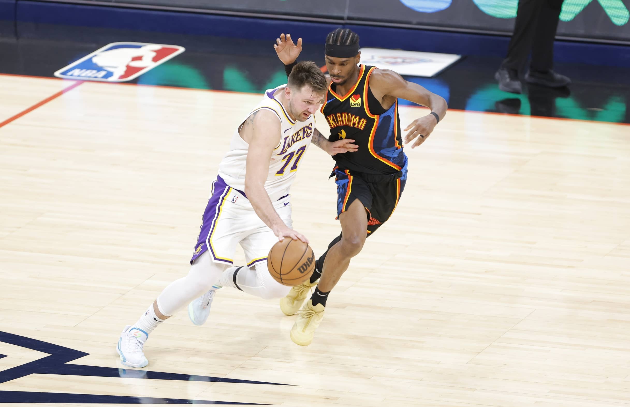 Oklahoma City, Oklahoma, USA; Los Angeles Lakers guard Luka Doncic (77) drives down the court beside Oklahoma City Thunder guard Shai Gilgeous-Alexander (2) during the second half at Paycom Center. Mandatory Credit: Alonzo Adams-Imagn Images