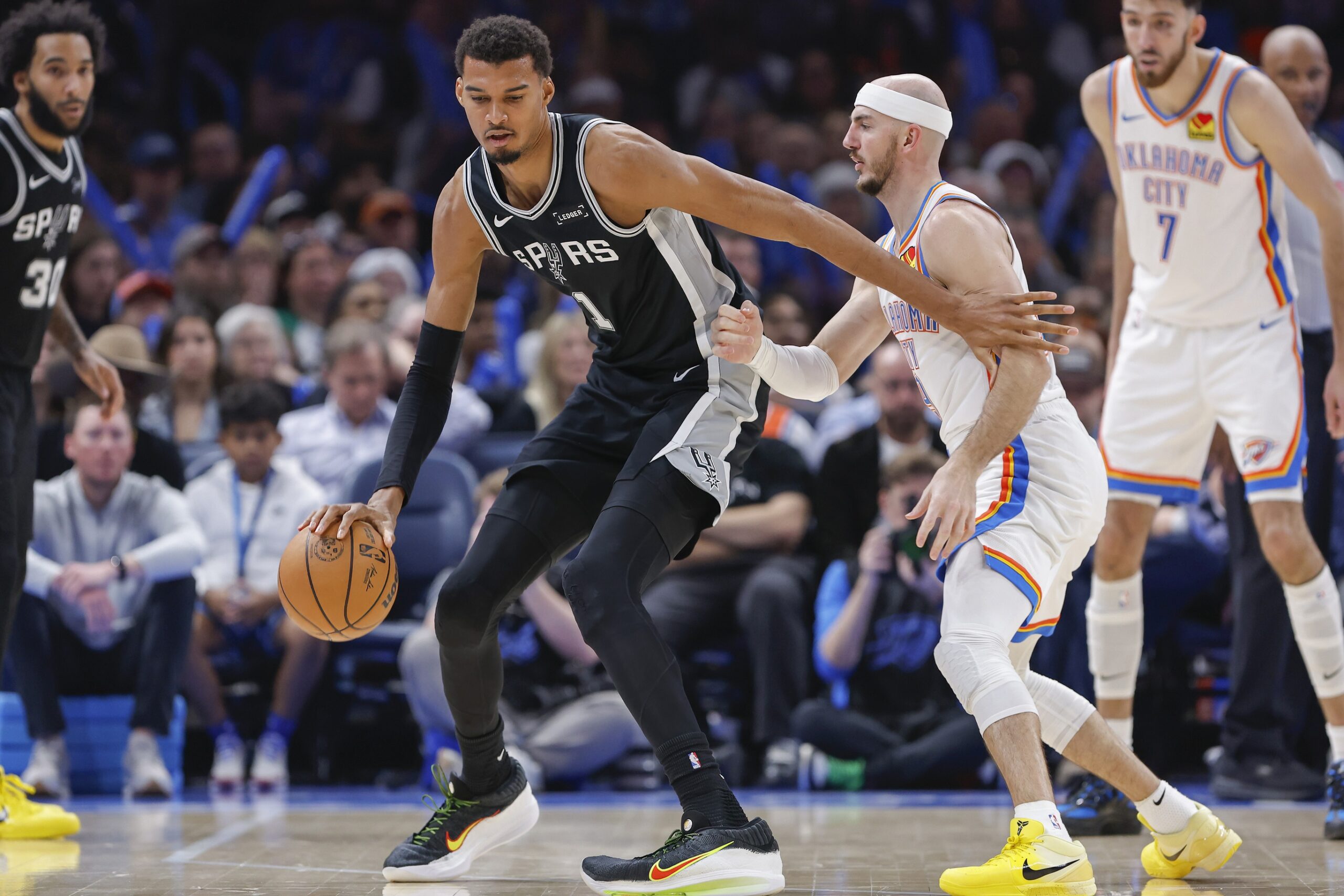 Dec 25, 2025; Oklahoma City, Oklahoma, USA; San Antonio Spurs forward Victor Wembanyama (1) moves the ball across the court against Oklahoma City Thunder guard Alex Caruso (9) during the second half at Paycom Center. Mandatory Credit: Alonzo Adams-Imagn Images