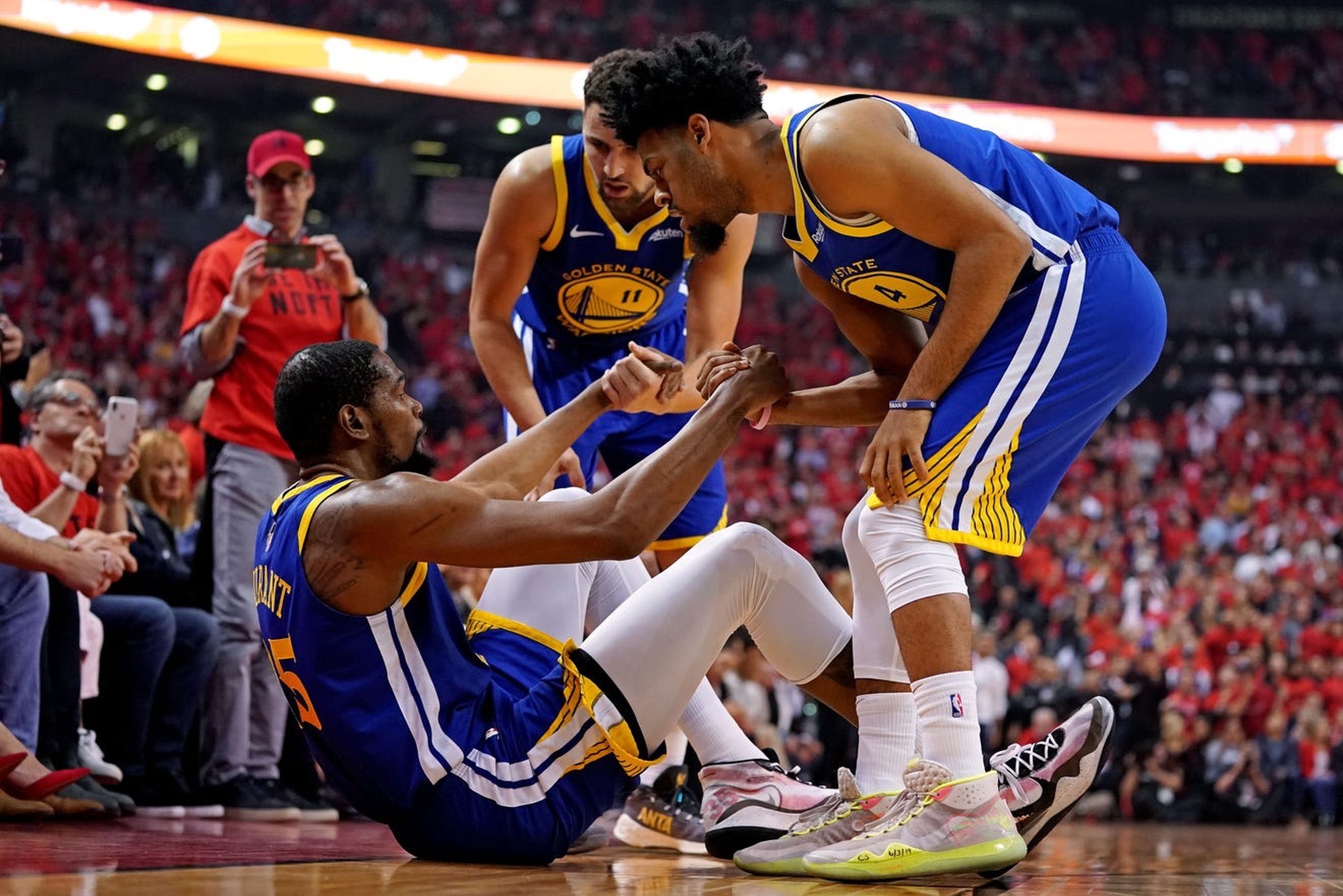 Jun 10, 2019; Toronto, Ontario, CAN; Golden State Warriors forward Kevin Durant (35) is helped up by guard Quinn Cook (4) and guard Klay Thompson (11) after an apparent injury during the second quarter in game five of the 2019 NBA Finals against the Toronto Raptors at Scotiabank Arena. Mandatory Credit: Kyle Terada-Imagn Images