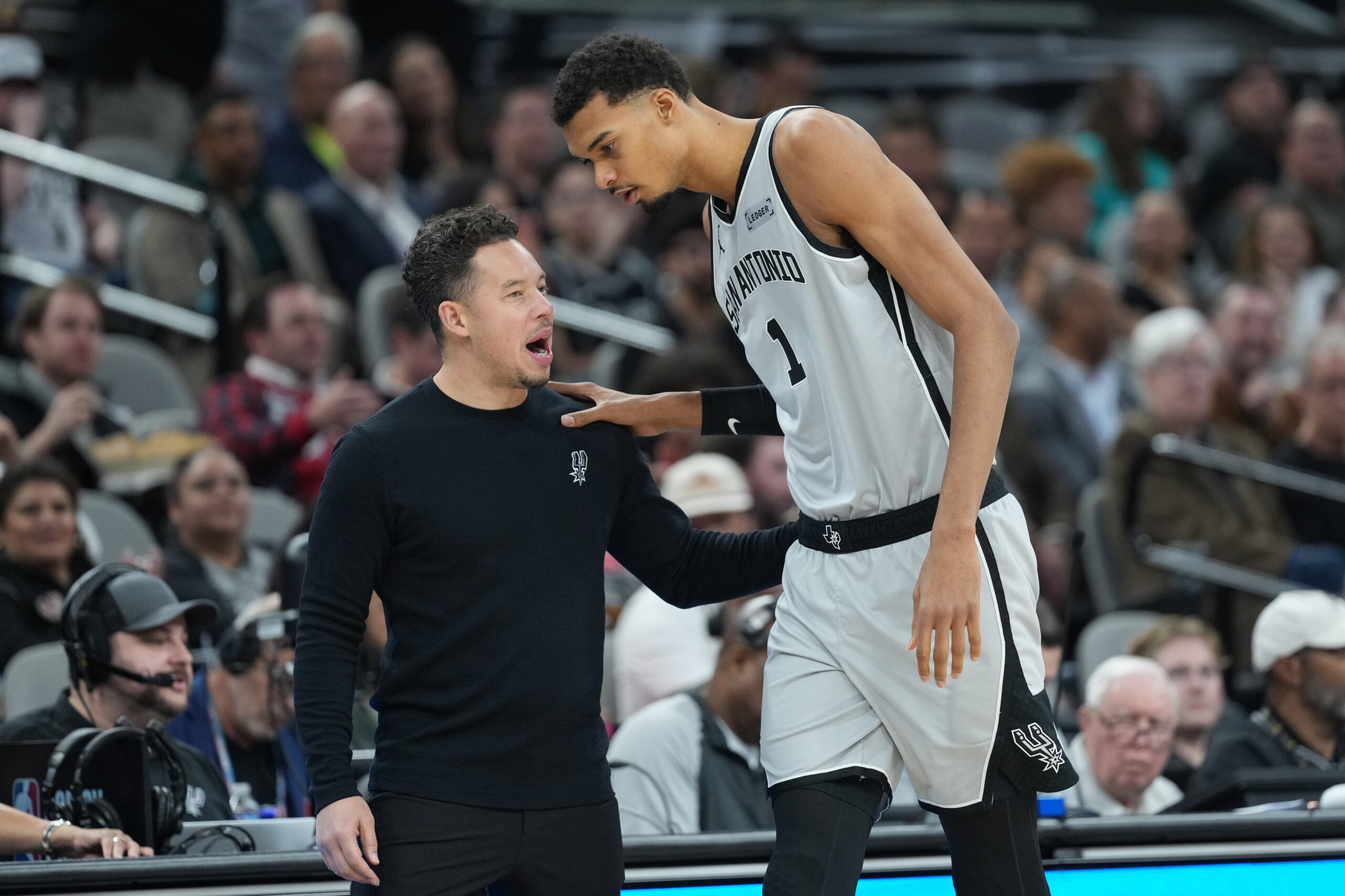 Dec 18, 2025; San Antonio, Texas, USA; San Antonio Spurs forward Victor Wembanyama (1) talks with head coach Mitch Johnson during the first half against the Washington Wizards at Frost Bank Center. Mandatory Credit: Scott Wachter-Imagn Images