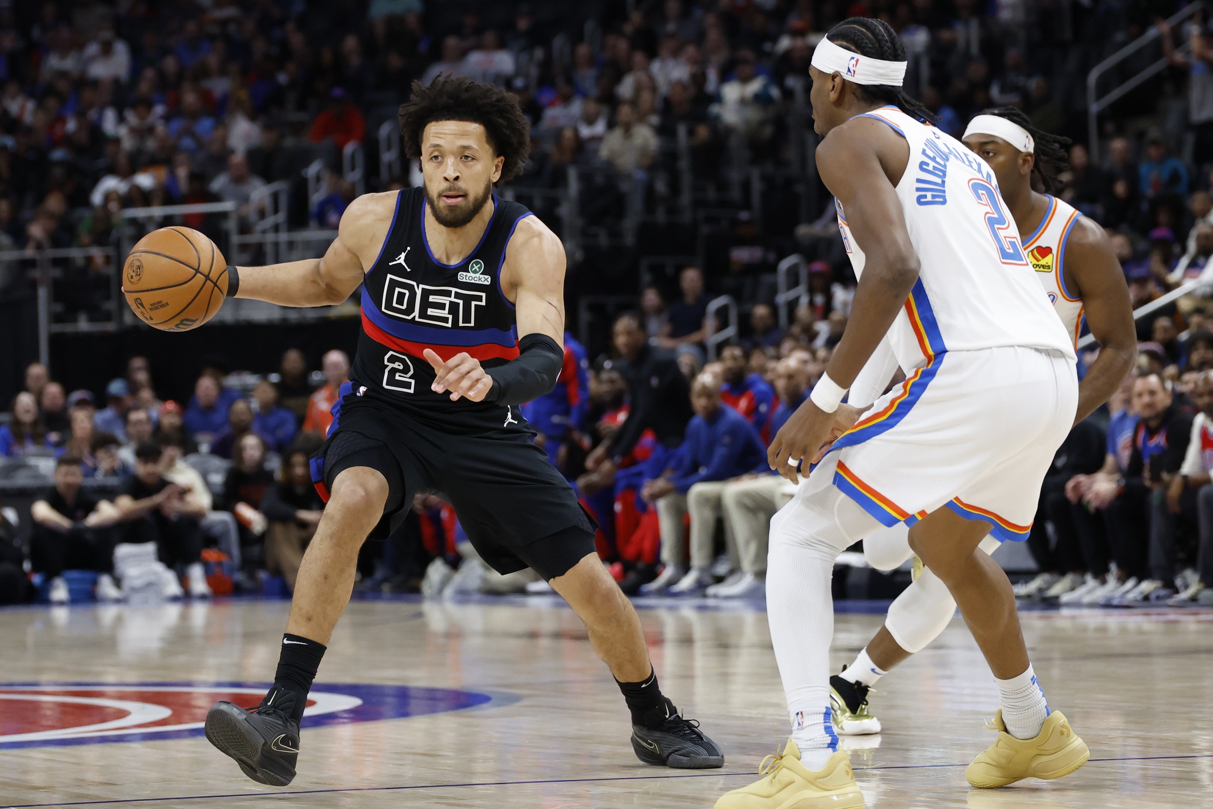 Mar 15, 2025; Detroit, Michigan, USA; Detroit Pistons guard Cade Cunningham (2) dribbles defended by Oklahoma City Thunder guard Shai Gilgeous-Alexander (2) in the first half at Little Caesars Arena. Mandatory Credit: Rick Osentoski-Imagn Images