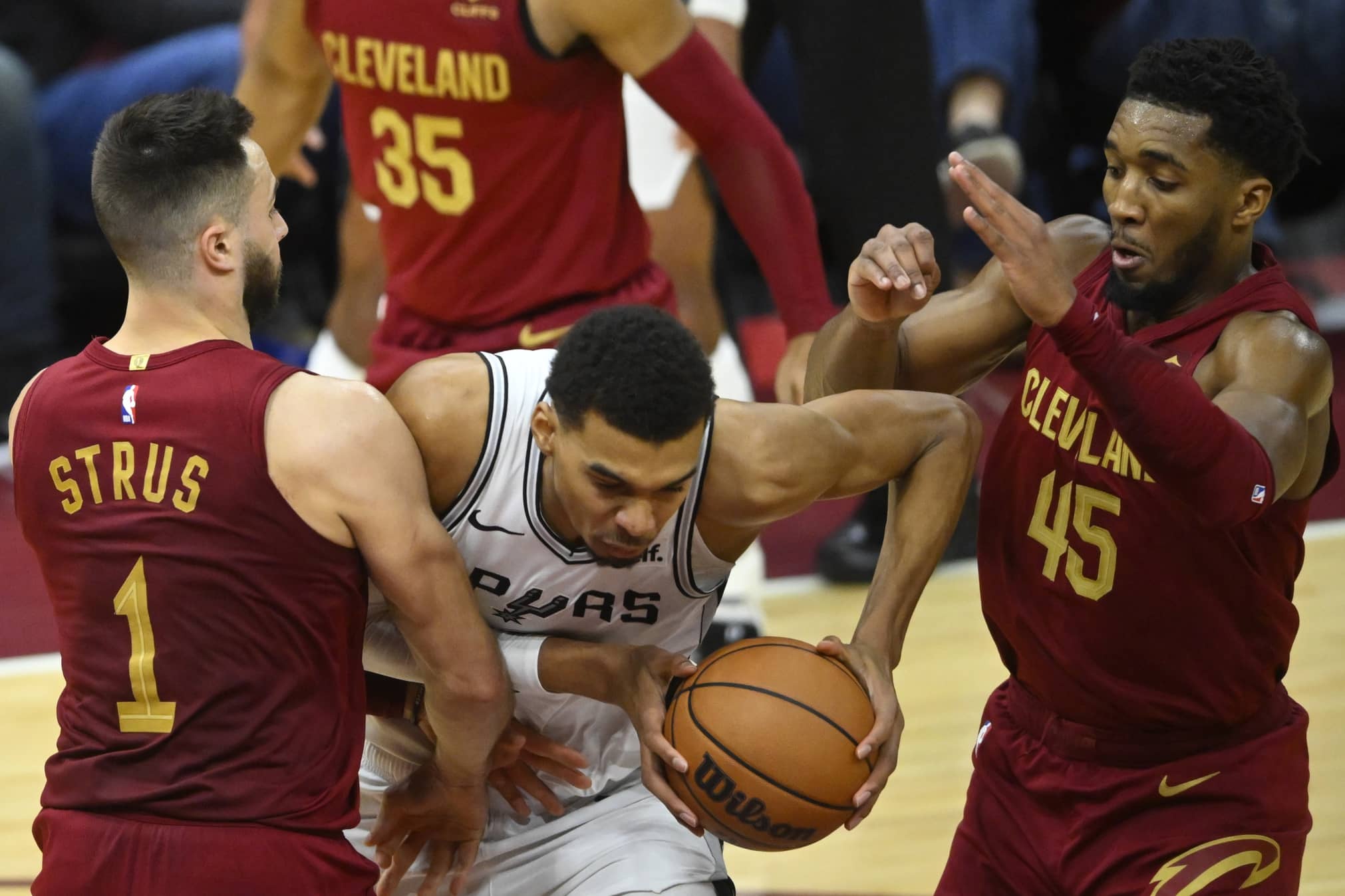 Jan 7, 2024; Cleveland, Ohio, USA; San Antonio Spurs center Victor Wembanyama (1) dribbles between Cleveland Cavaliers guard Max Strus (1) and guard Donovan Mitchell (45) in the fourth quarter at Rocket Mortgage FieldHouse. Mandatory Credit: David Richard-Imagn Images