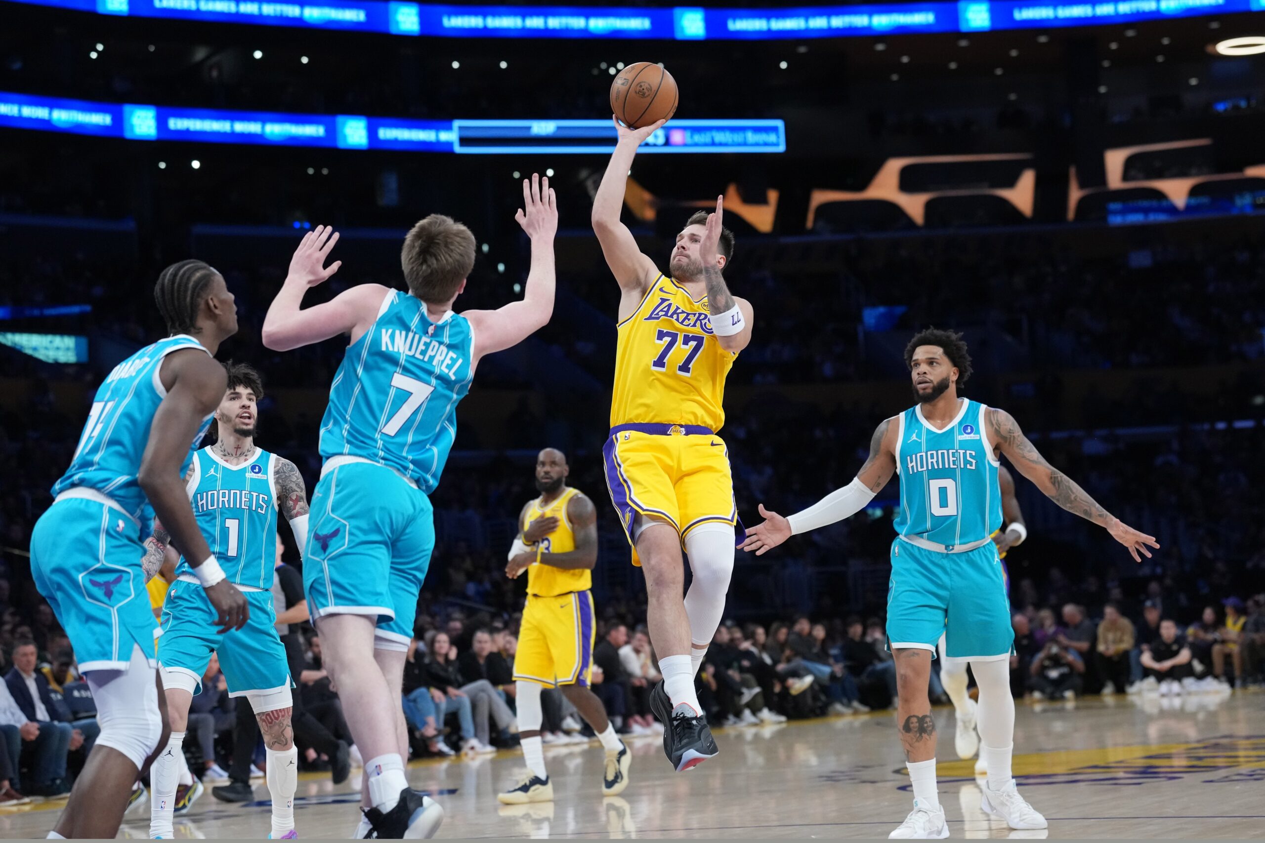 Jan 15, 2026; Los Angeles, California, USA; Los Angeles Lakers guard Luka Doncic (77) shoots the ball against Charlotte Hornets guard Kon Knueppel (7) and forward Miles Bridges (0) in the first half at Crypto.com Arena. Mandatory Credit: Kirby Lee-Imagn Images