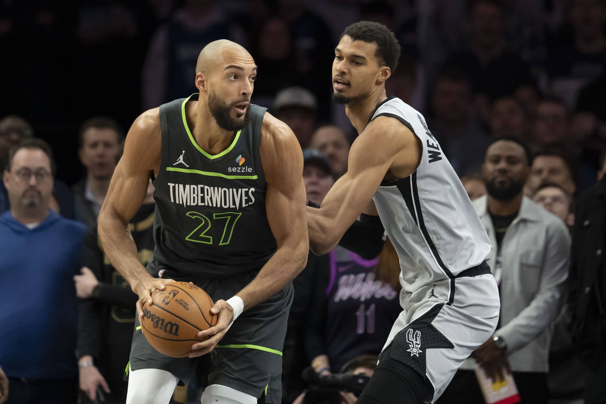 Jan 11, 2026; Minneapolis, Minnesota, USA; Minnesota Timberwolves center Rudy Gobert (27) holds the ball as San Antonio Spurs forward Victor Wembanyama (1) plays defense in the first half at Target Center. Mandatory Credit: Jesse Johnson-Imagn Images