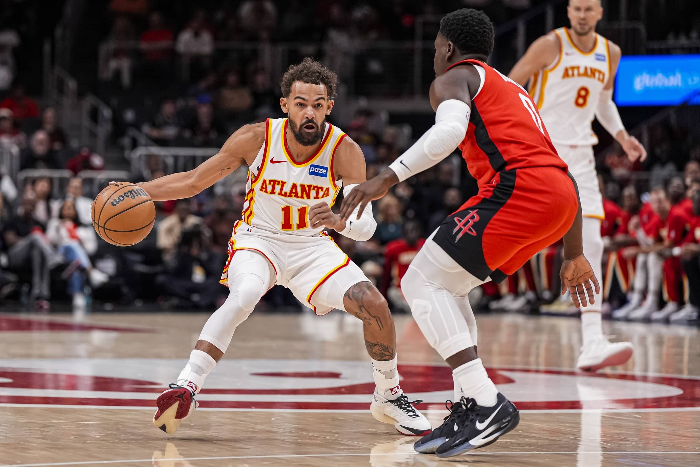 Oct 16, 2025; Atlanta, Georgia, USA; Atlanta Hawks point guard Trae Young (11) dribbles against Houston Rockets guard Aaron Holiday (0) during the first half at State Farm Arena. Mandatory Credit: Dale Zanine-Imagn Images