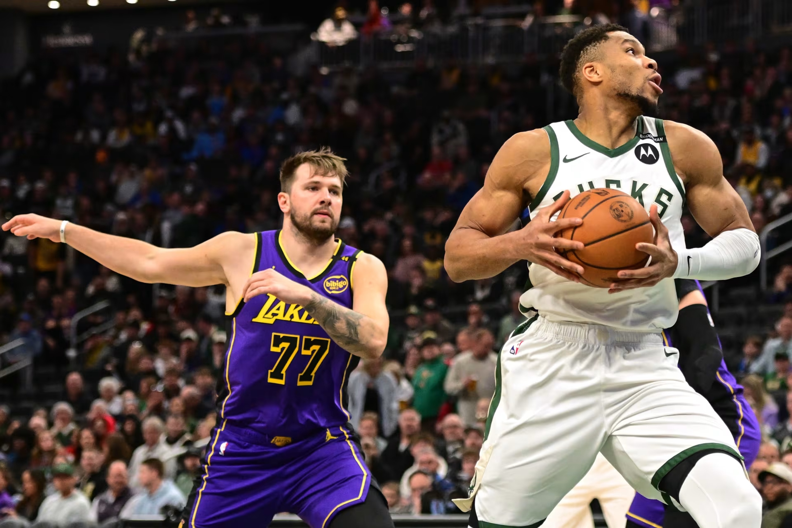 Mar 13, 2025; Milwaukee, Wisconsin, USA; Milwaukee Bucks forward Giannis Antetokounmpo (34) controls the ball against Los Angeles Lakers guard Luka Doncic (77) in the first quarter at Fiserv Forum. Mandatory Credit: Benny Sieu-Imagn Images
