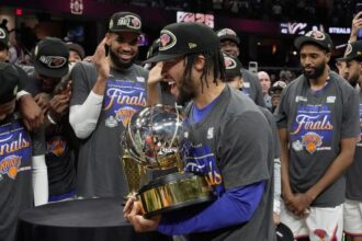 New York Knicks guard Jalen Brunson, center, holds the Eastern Conference Championship trophy after Game 4 in the Eastern Conference finals NBA basketball playoffs series against the Cleveland Cavaliers in Cleveland, Monday, May 25, 2026. (AP Photo/Sue Ogrocki)