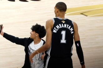 SAN ANTONIO, TEXAS - JUNE 03: A fan runs onto the court and takes a photo with Victor Wembanyama #1 of the San Antonio Spurs during the fourth quarter in Game One of the 2026 NBA Finals against the New York Knicks at Frost Bank Center on June 03, 2026 in San Antonio, Texas. (Photo by Ronald Cortes/Getty Images)